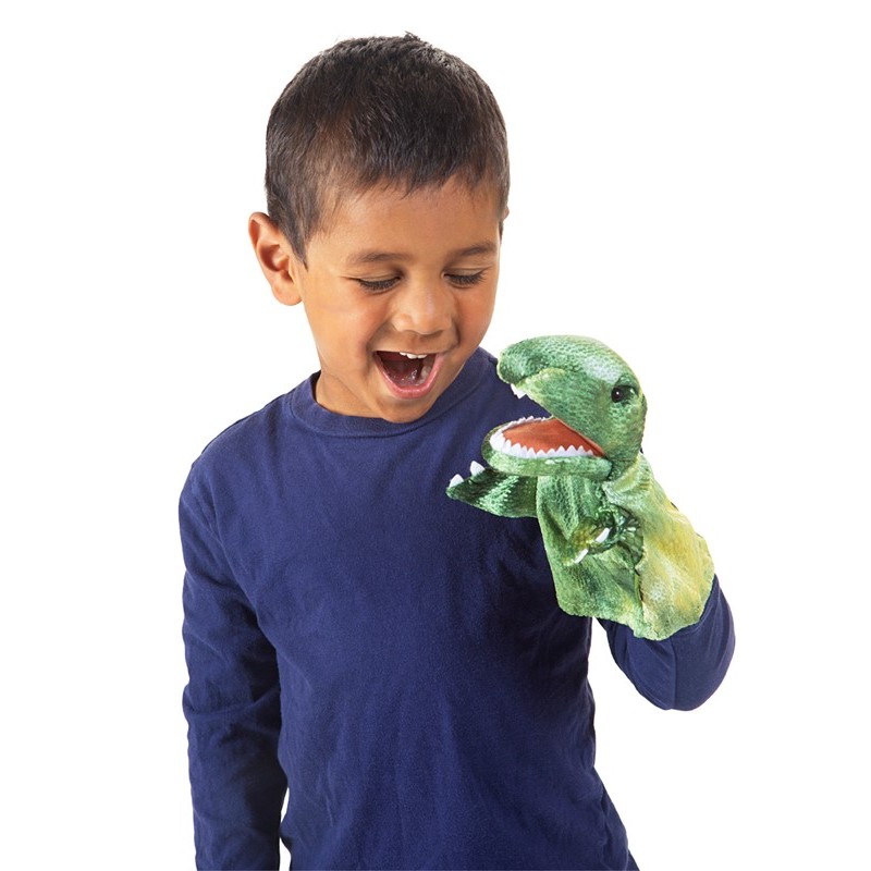 Junge lacht, während er eine grüne Folkmanis Handpuppe kleiner T-Rex mit geöffnetem Maul und weißen Zähnen auf der Hand trägt.