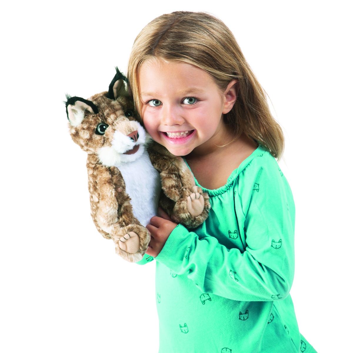 Girl in a green top smiling at the camera while holding a Folkmanis bobcat kitten hand puppet with spotted fur and black ear tufts