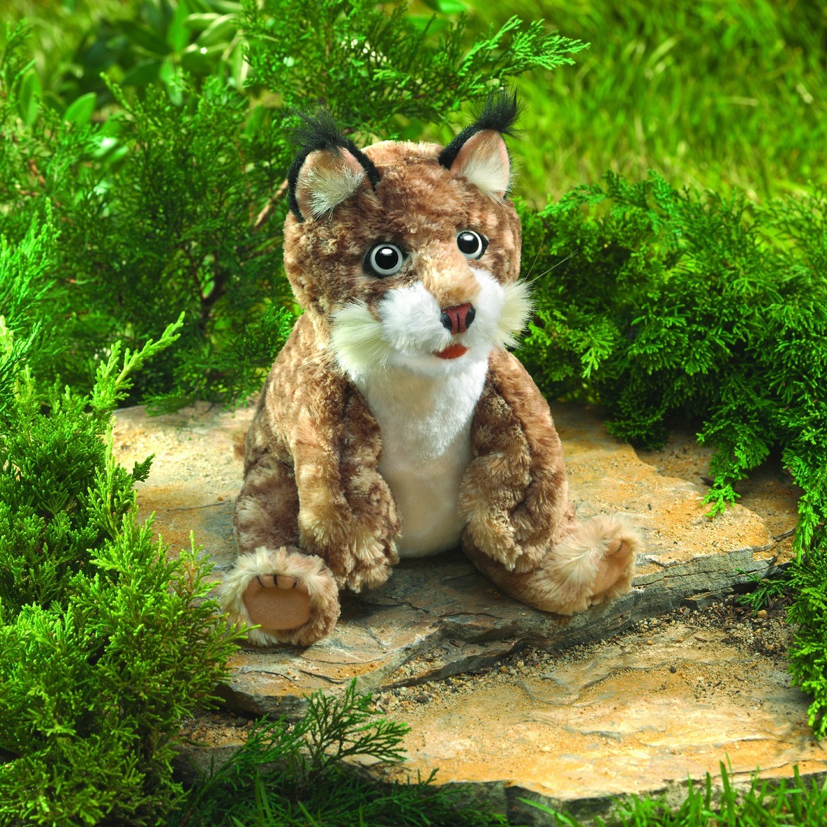 Folkmanis Handpuppe Rotluchs-Baby sitzend auf Stein, braun-geflecktes Fell, schwarze Ohrpinsel, weißer Bauch, geöffnetes Maul