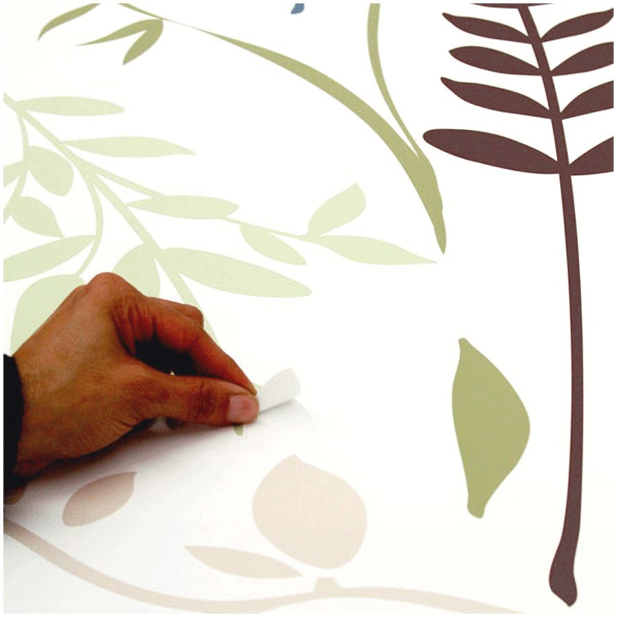 RoomMates wall decal Multi Branches, hand peeling a brown leaf motif off the backing sheet among green branches