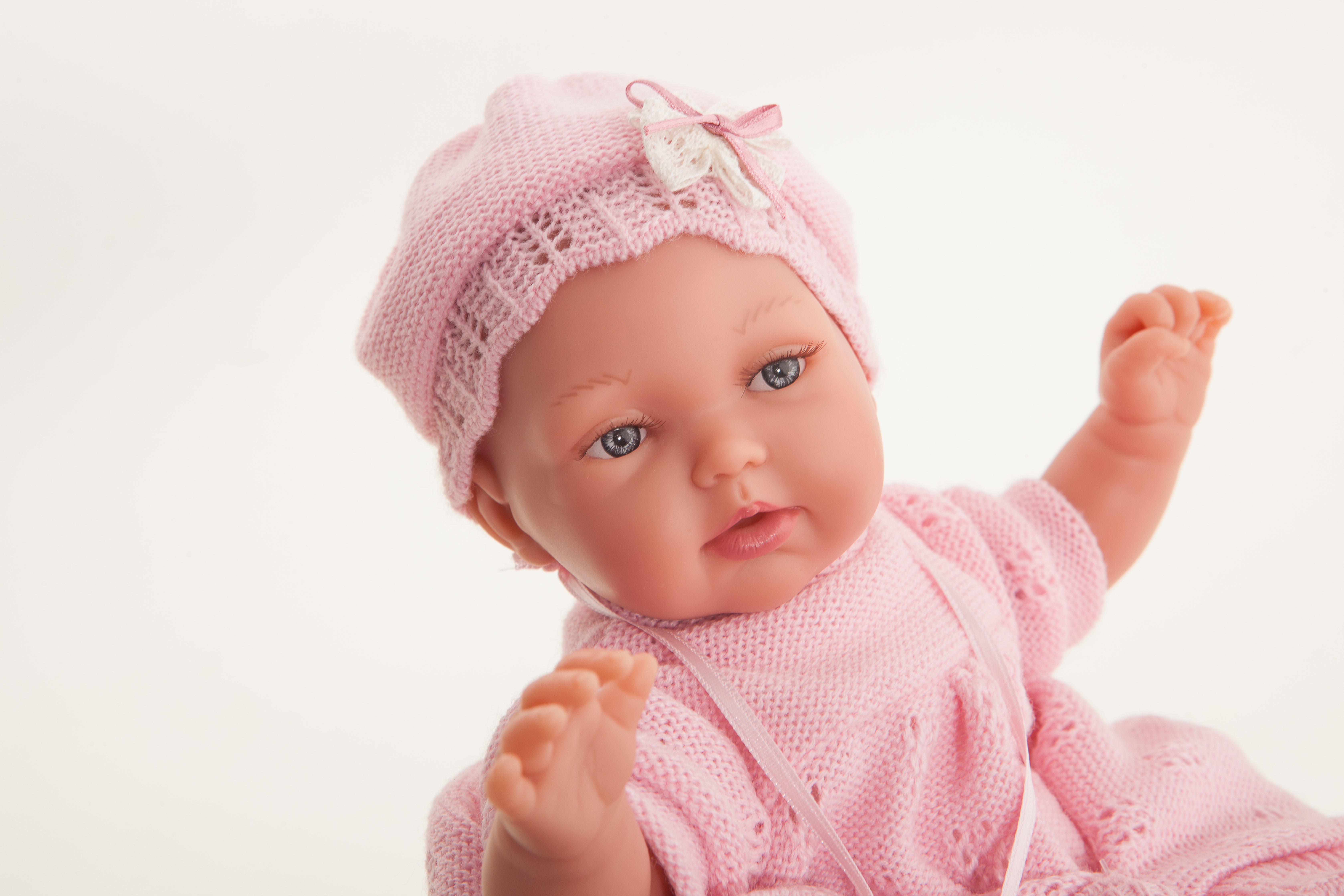 Antonio Juan Babypuppe Peke, Gesichts-Nahaufnahme mit blauen Augen und rosa Häkelmütze mit Schleife