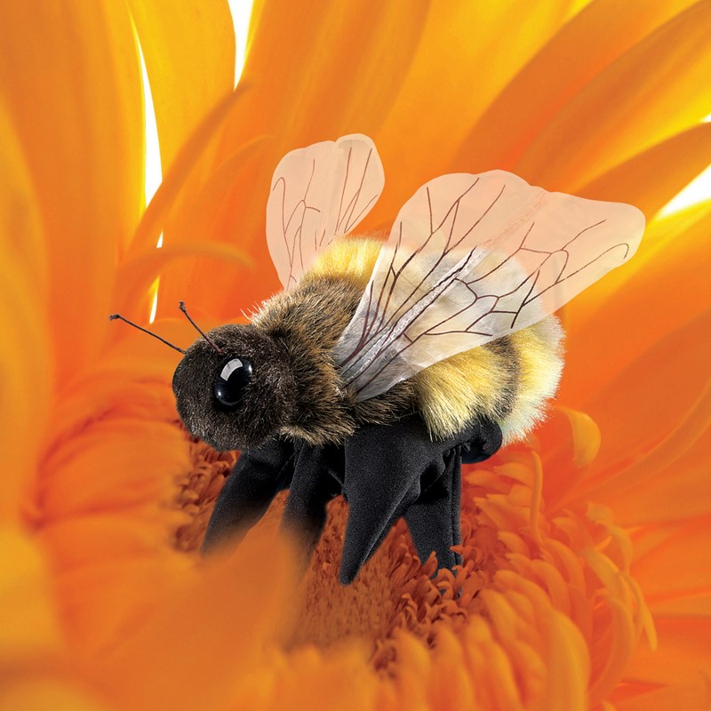 Folkmanis Handpuppe Biene mit schwarz-gelbem Plüschkörper und transparenten Flügeln, von oben auf einer orangefarbenen Blüte fotografiert