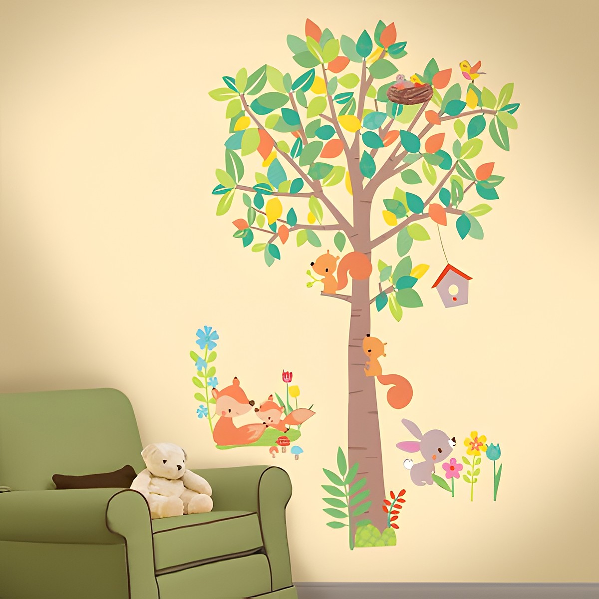RoomMates Wandbild Woodland Waldtiere Baum, bunter Baum mit Eichhörnchen, Vogelnest und Vogelhäuschen an einer cremefarbenen Kinderzimmerwand neben einem Sessel