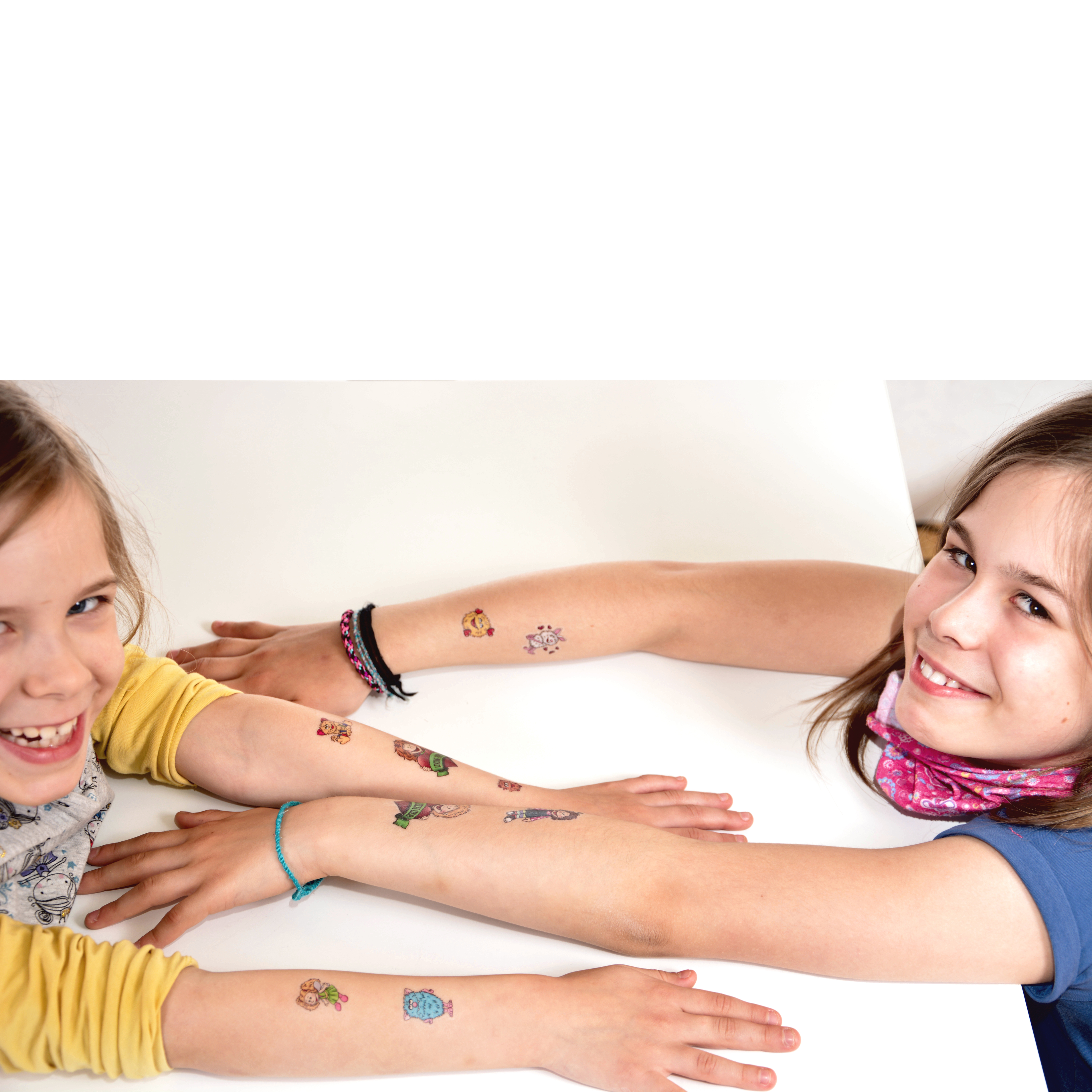 Children showing colourful Living Puppets tattoos on their forearms, smiling at a table, usage example