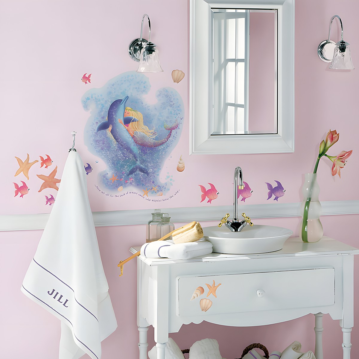 RoomMates wall decal Mermaid, mermaid with a dolphin surrounded by fish and starfish on a pink bathroom wall above a vanity unit