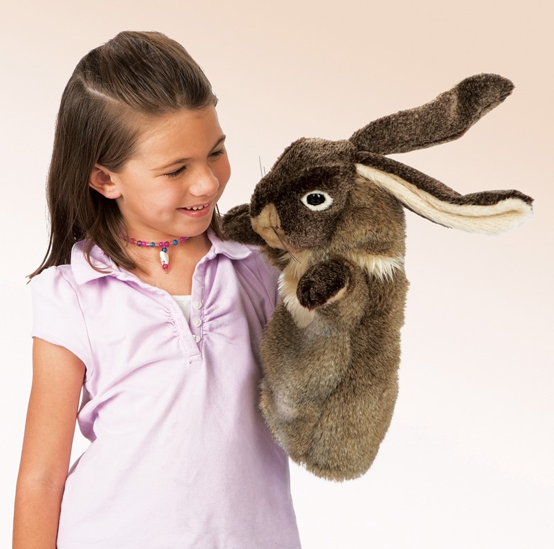 Mädchen führt eine große Folkmanis Kaninchen-Handpuppe mit braunem Fell und langen Ohren an ihrer Schulter