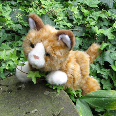 Living Puppets Handpuppe Braune Katze liegt zwischen Efeuranken im Garten