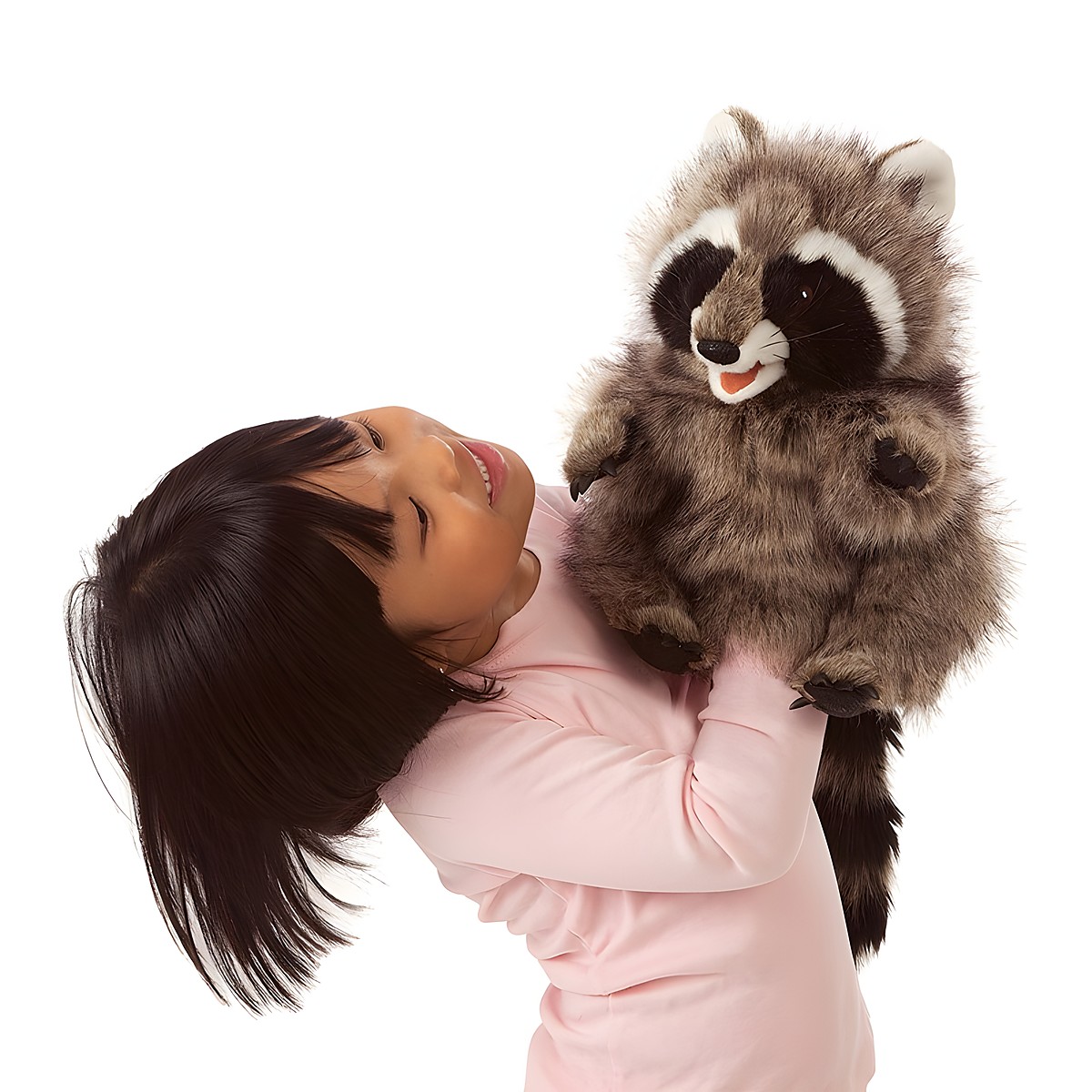 Mädchen hält Folkmanis Handpuppe Waschbär mit geöffnetem Maul in die Höhe, grau-braunes Fell mit schwarzer Gesichtsmaske.