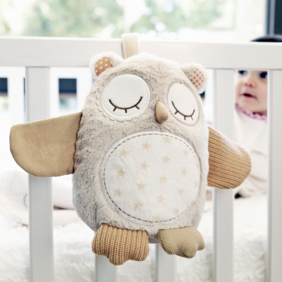 Cloud b Einschlafhilfe Nighty Night Owl, Anwendungsfoto: Eulen-Kuscheltier hängt am Gitterbett, Baby im Hintergrund