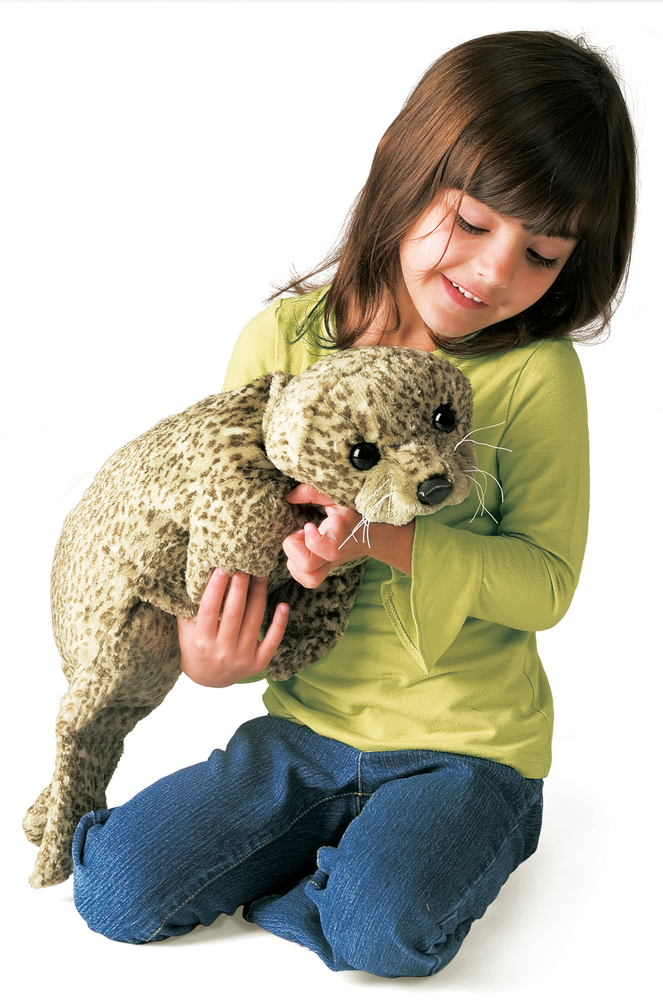 Mädchen hält die Folkmanis Handpuppe Seehund mit beiger Fleckenfell-Textur und weißen Schnurrhaaren in beiden Händen.