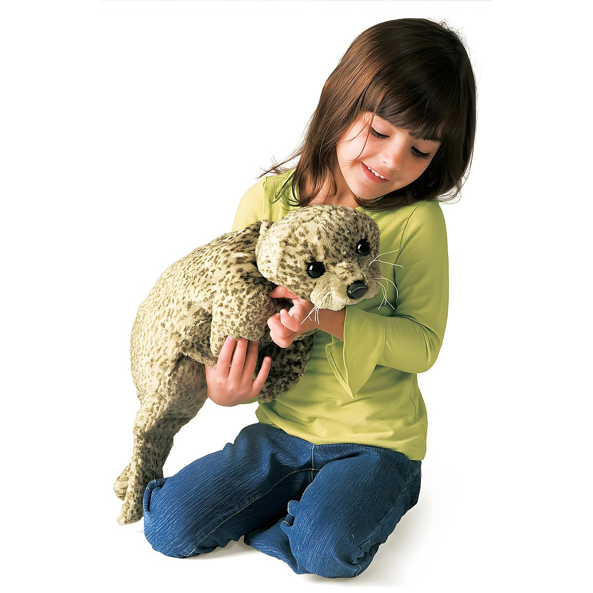 Mädchen hält die Folkmanis Handpuppe Seehund mit beiger Fleckenfell-Textur und weißen Schnurrhaaren in beiden Händen.