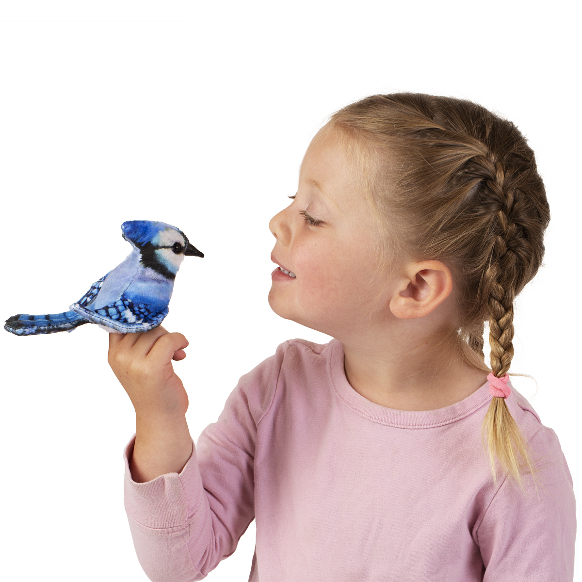Girl holding a Folkmanis mini blue jay finger puppet with blue-and-white plumage on her index finger, smiling at it