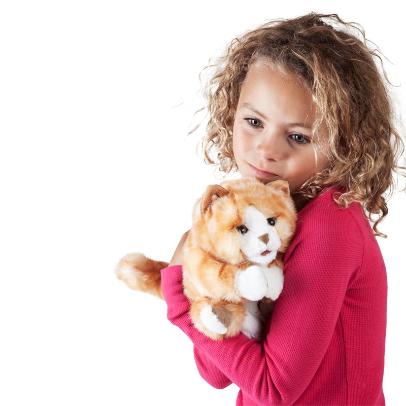 Mädchen mit lockigem Haar hält die orange-braune Kätzchen-Handpuppe von Folkmanis mit weißer Brust im Arm