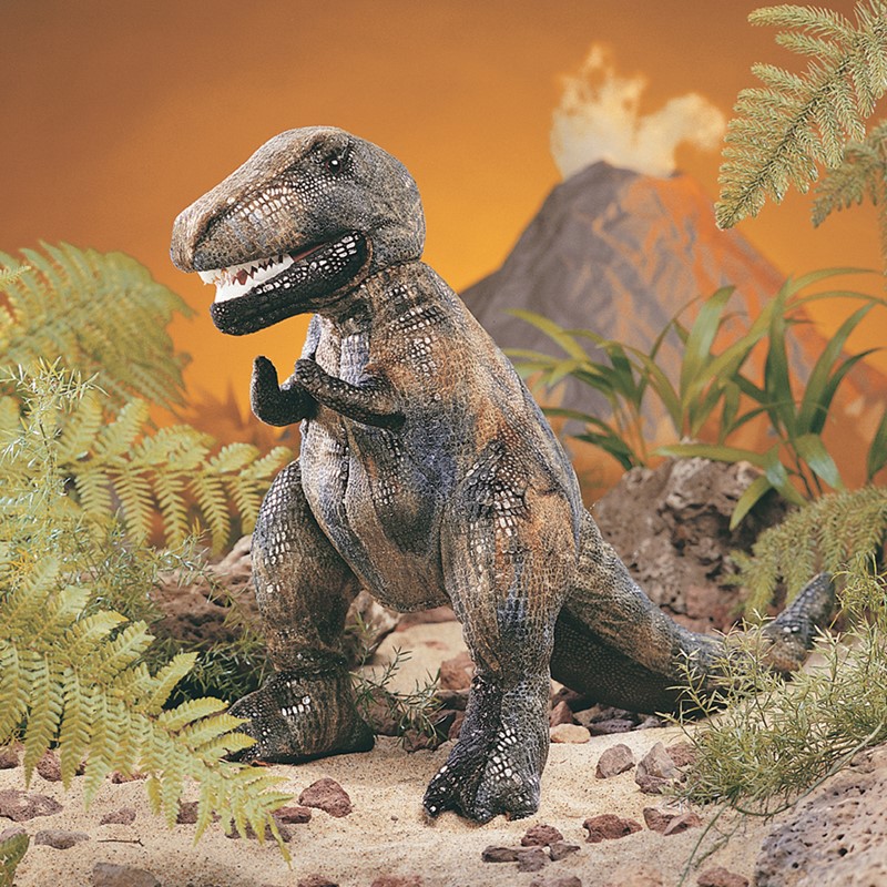 Folkmanis Handpuppe kleiner Tyrannosaurus Rex mit aufgerissenem Maul, detaillierter Schuppenstruktur, vor Urzeitkulisse mit Vulkan