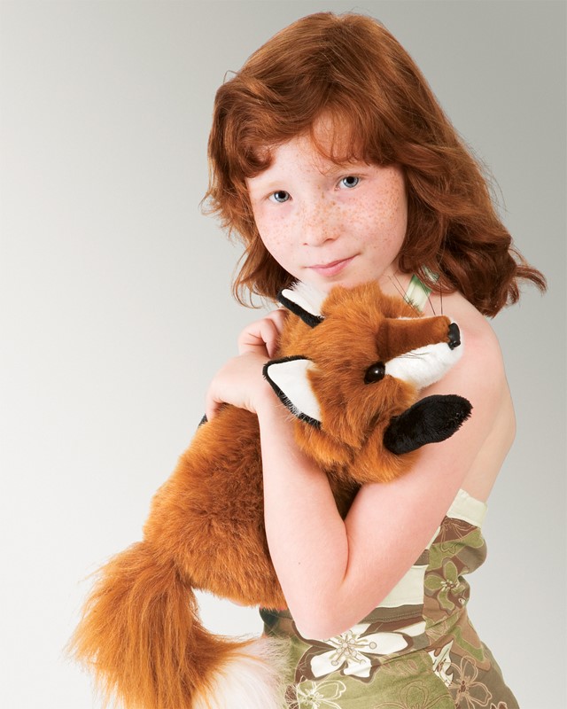 Mädchen hält die Folkmanis Handpuppe kleiner Rotfuchs mit rotbraunem Fell, weißer Brust und schwarzen Pfoten im Arm.