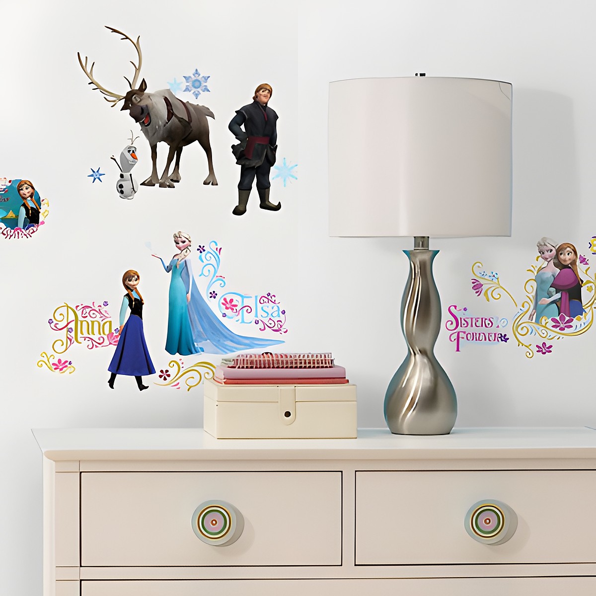 RoomMates wall decal Disney Frozen, motifs with Elsa, Anna, Olaf, Sven and Kristoff plus lettering on a white children's room wall above a chest of drawers