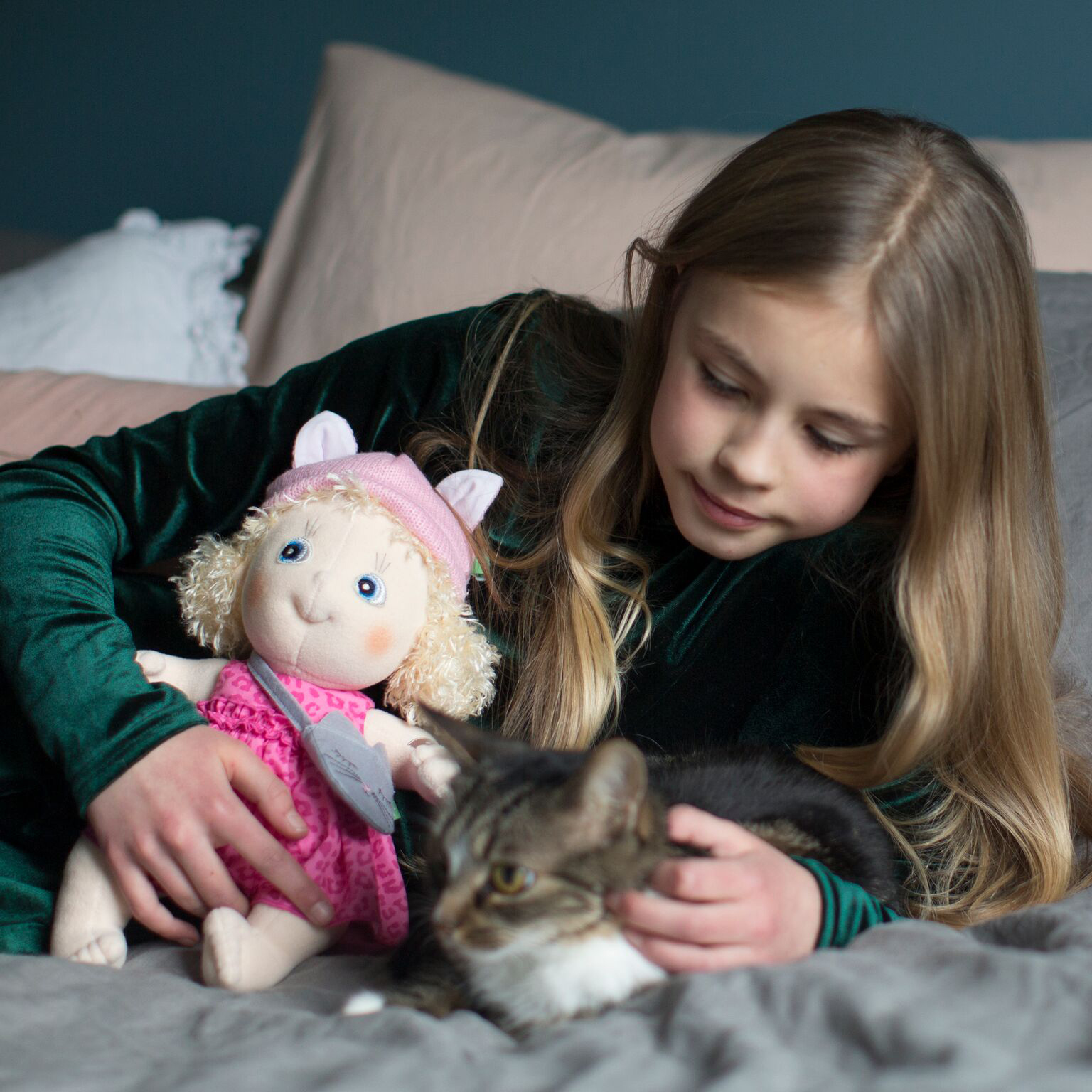 Child with the Rubens Cutie doll Emelie petting a cat on the bed