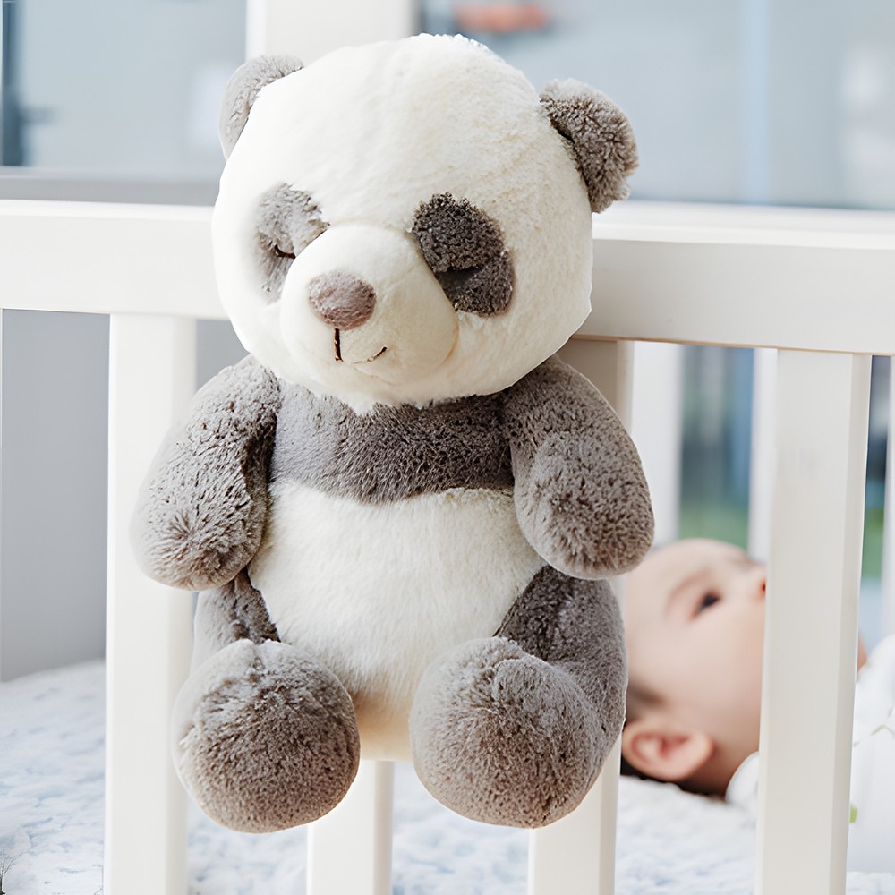 Cloud b Einschlafhilfe Peaceful Panda, Anwendungsfoto: Panda-Kuscheltier hängt am Gitterbett, Baby im Hintergrund