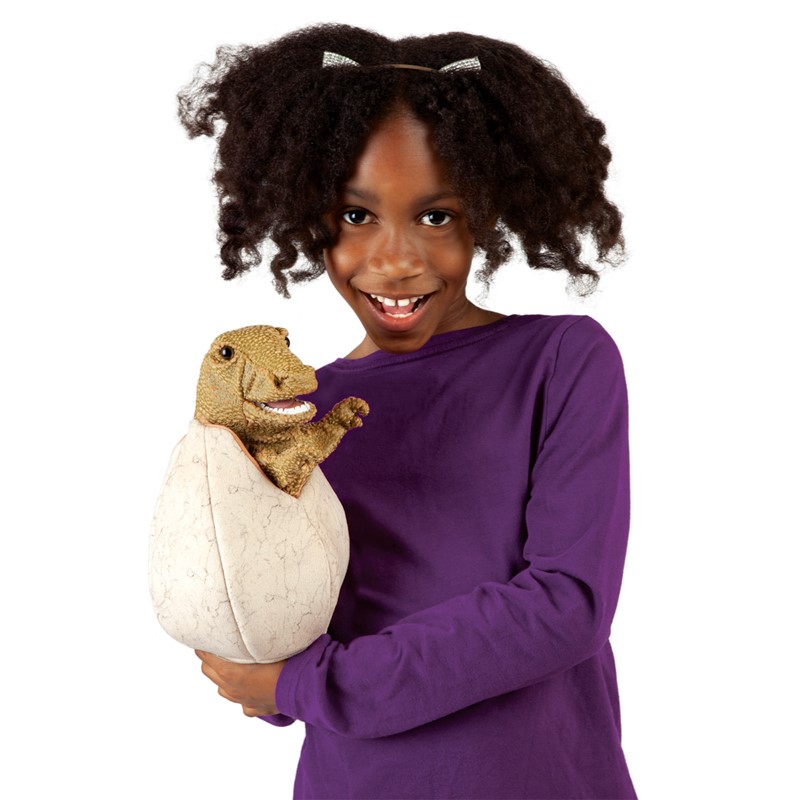 Mädchen hält Folkmanis Handpuppe Saurierbaby im Ei, braun-grüner Dinosaurier lugt aus cremefarbenem Ei hervor.