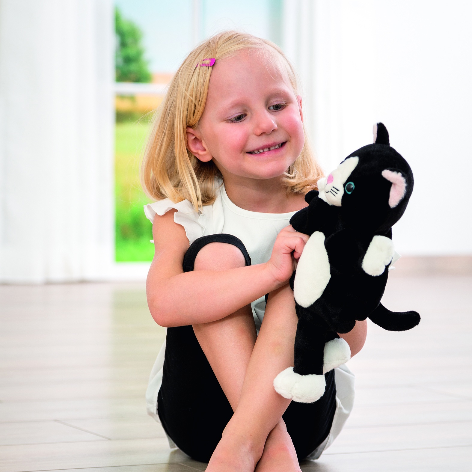 Girl cuddling the Beleduc story hand puppet cat Cara, usage example