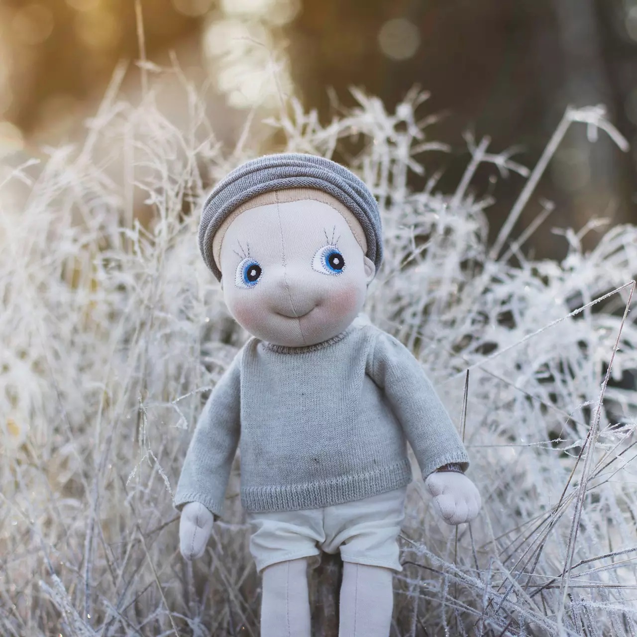 Rubens EcoBuds doll in the winter outfit with knitted hat in frosty winter grass