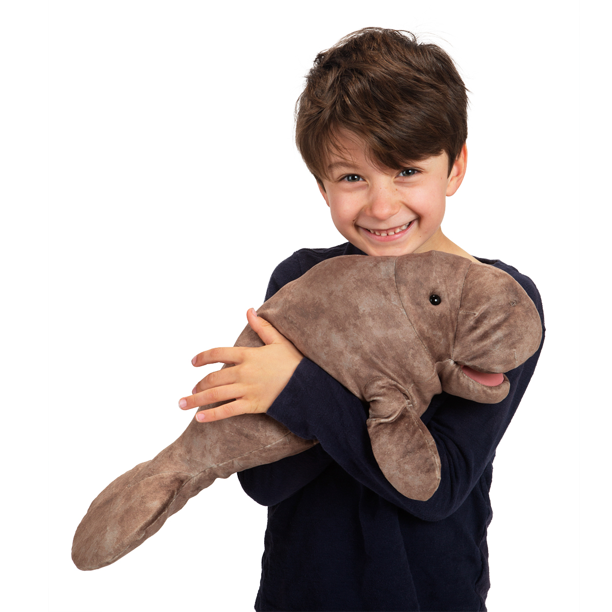 Lachender Junge hält die Folkmanis Handpuppe Seekuh aus graubraunem Plüsch mit beiden Armen fest umschlungen.