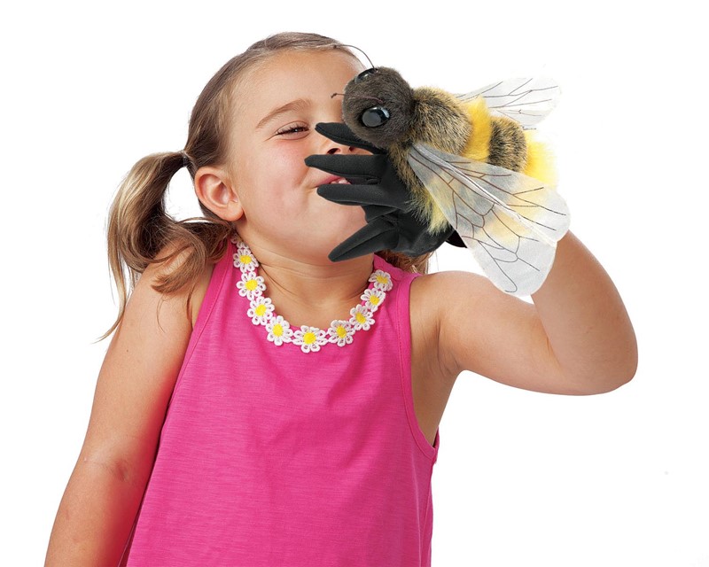 Mädchen hält Folkmanis Handpuppe Biene mit schwarzem Handschuh, gelb-schwarzem Plüsch und transparenten Flügeln ans Gesicht.