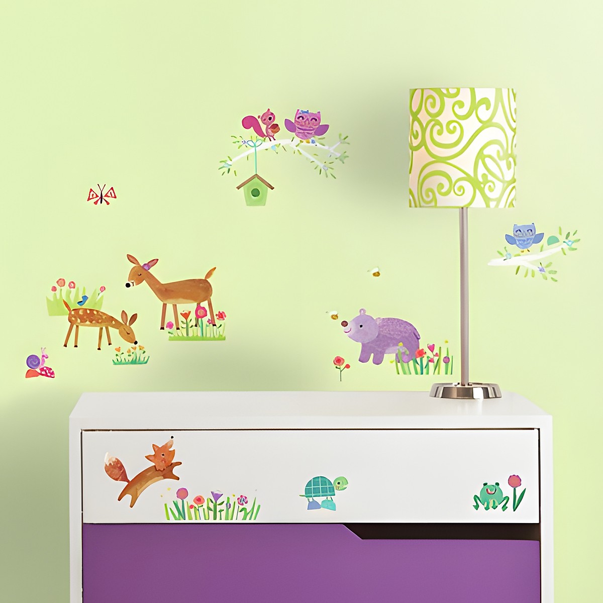 RoomMates wall decal Woodland Baby, woodland animals such as a deer, fox, owl and squirrel with flowers on a green children's room wall above a purple chest of drawers