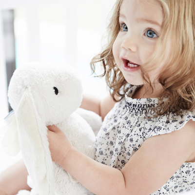 Cloud b Einschlafhilfe Bubbly Bunny, Anwendungsfoto: Kleinkind hält beiges Hasen-Kuscheltier, Nahaufnahme