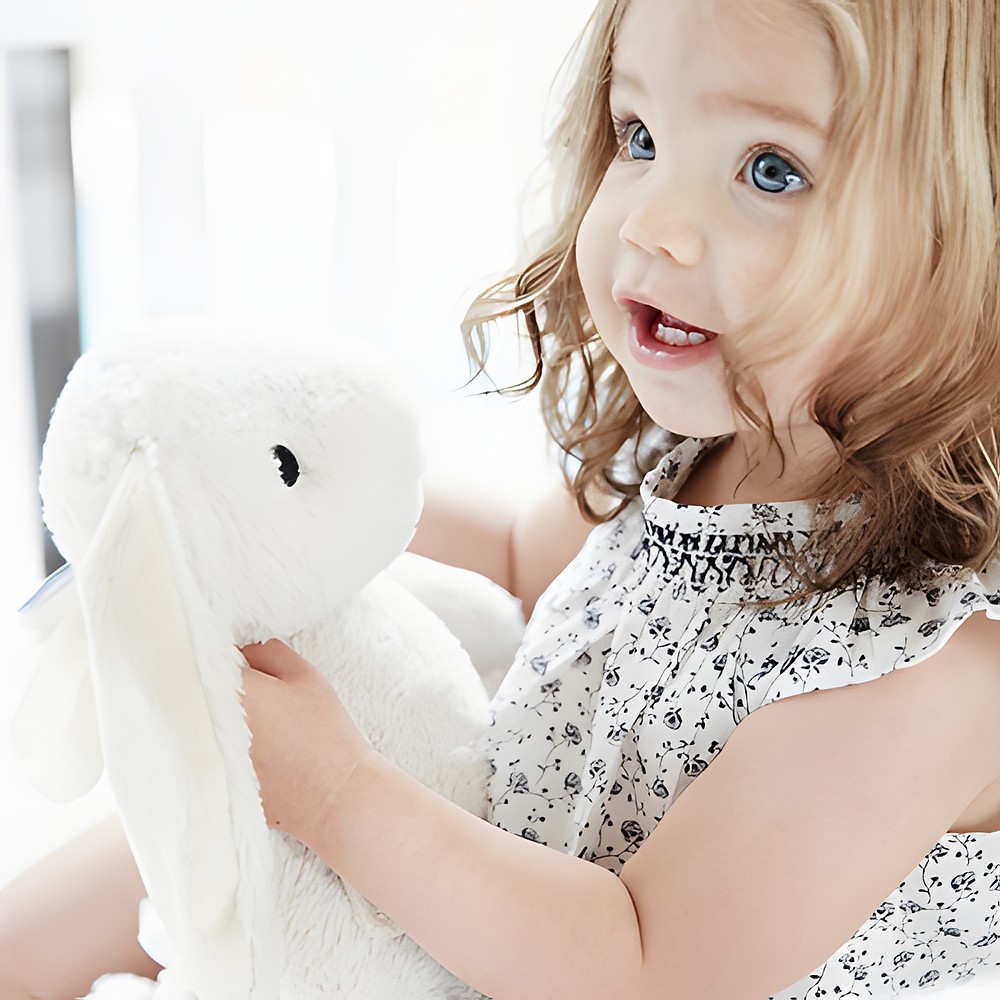 Cloud b Einschlafhilfe Bubbly Bunny, Anwendungsfoto: Kleinkind hält beiges Hasen-Kuscheltier, Nahaufnahme