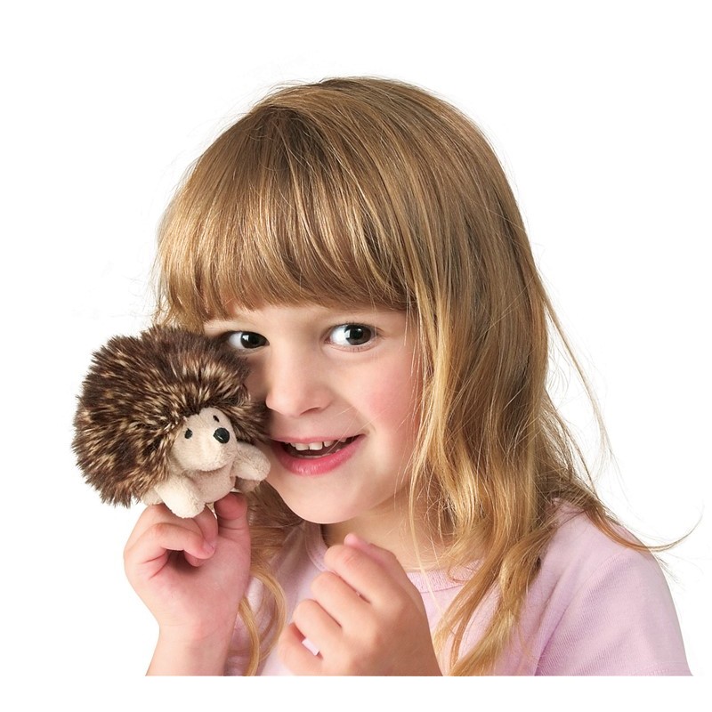 Mädchen hält winzige Folkmanis Fingerpuppe Mini-Igel mit braunem Stachelrücken und hellem Bauch nah ans Gesicht