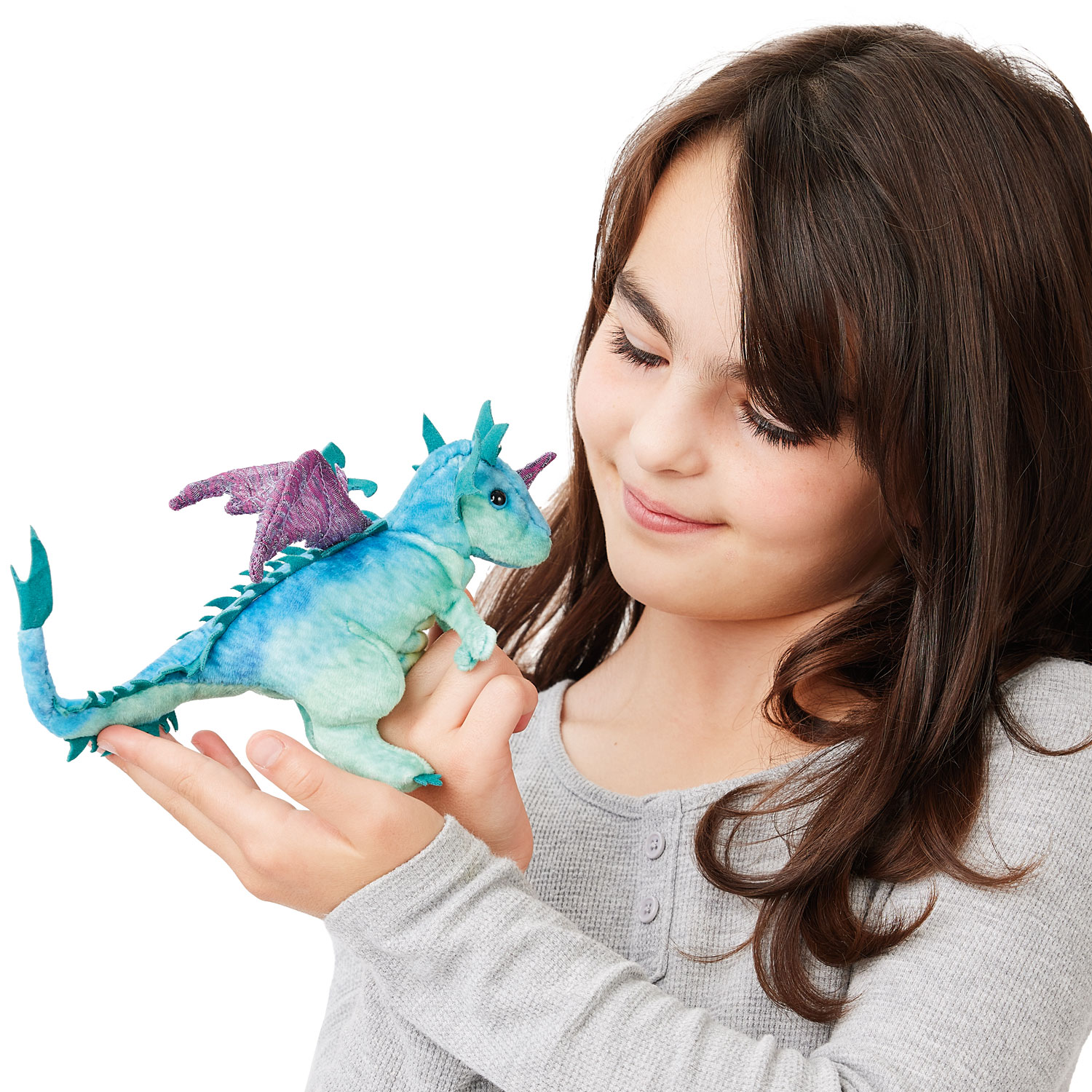 Girl holding a Folkmanis mini dragon finger puppet in blue-green with purple wings on the palm of her hand