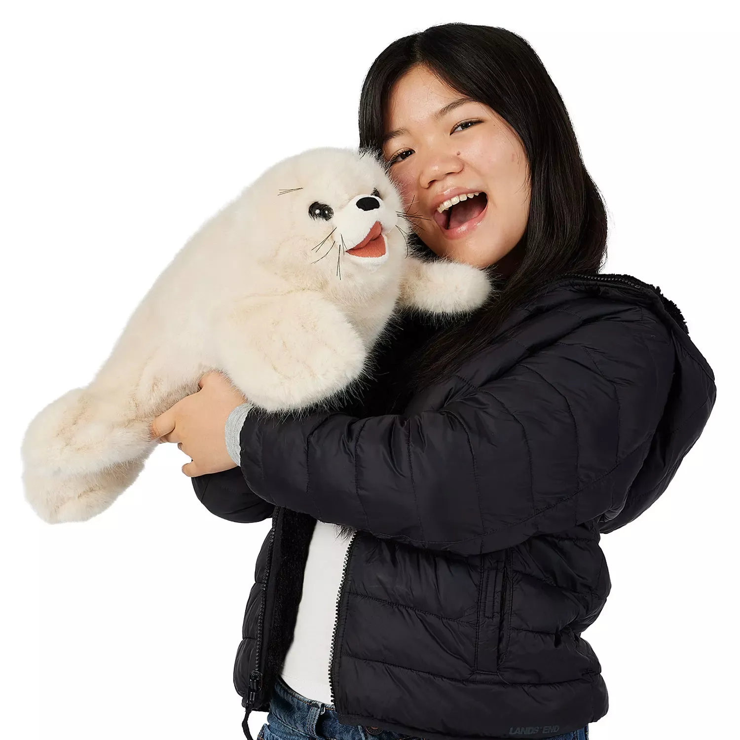 Mädchen hält große Folkmanis Handpuppe Robbenbaby mit weißem Plüschfell, schwarzen Augen und geöffnetem Maul im Arm.