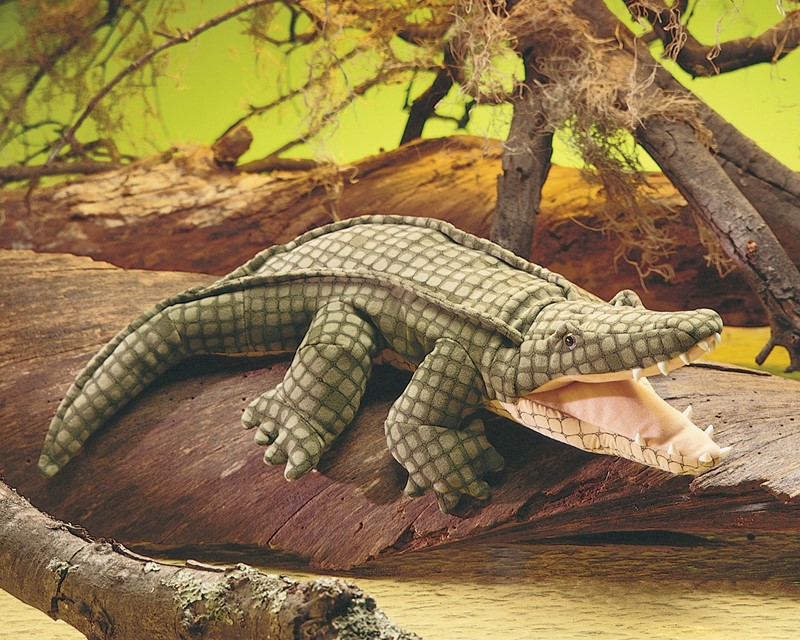 Folkmanis Handpuppe Krokodil mit geöffnetem Maul und detaillierter grüner Schuppentextur, auf einem Baumstamm liegend