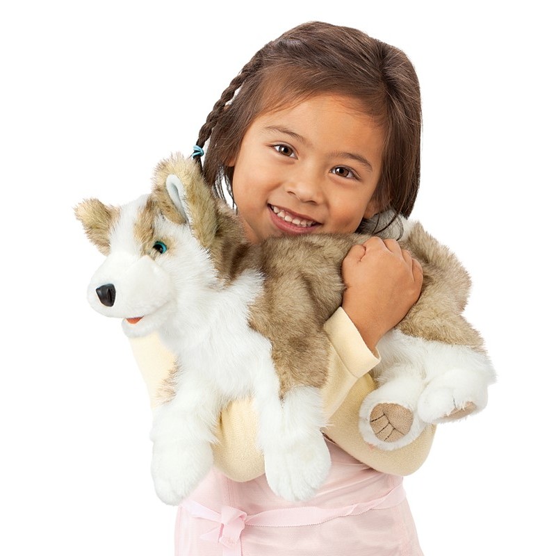 Mädchen hält Folkmanis Handpuppe Wolfsjunges mit grau-weißem Plüschfell und blauen Augen im Arm