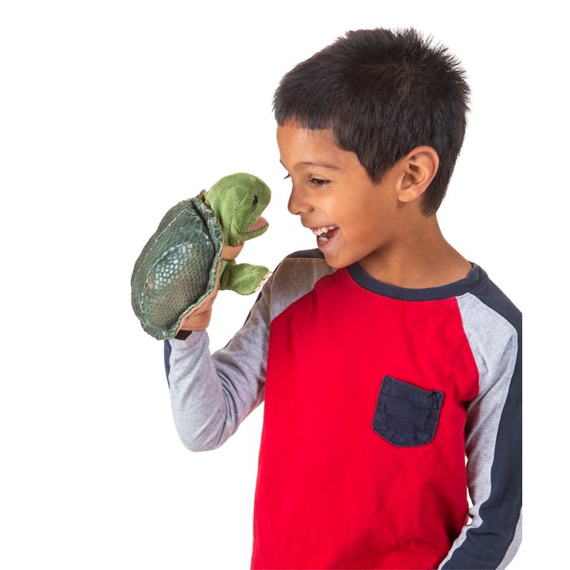 Junge hält Folkmanis Handpuppe kleine Schildkröte mit geöffnetem Maul auf der Hand und lacht sie an