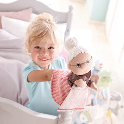 HABA Baby-Handpuppe Oma, Anwendungsfoto mit einem Mädchen im Bett