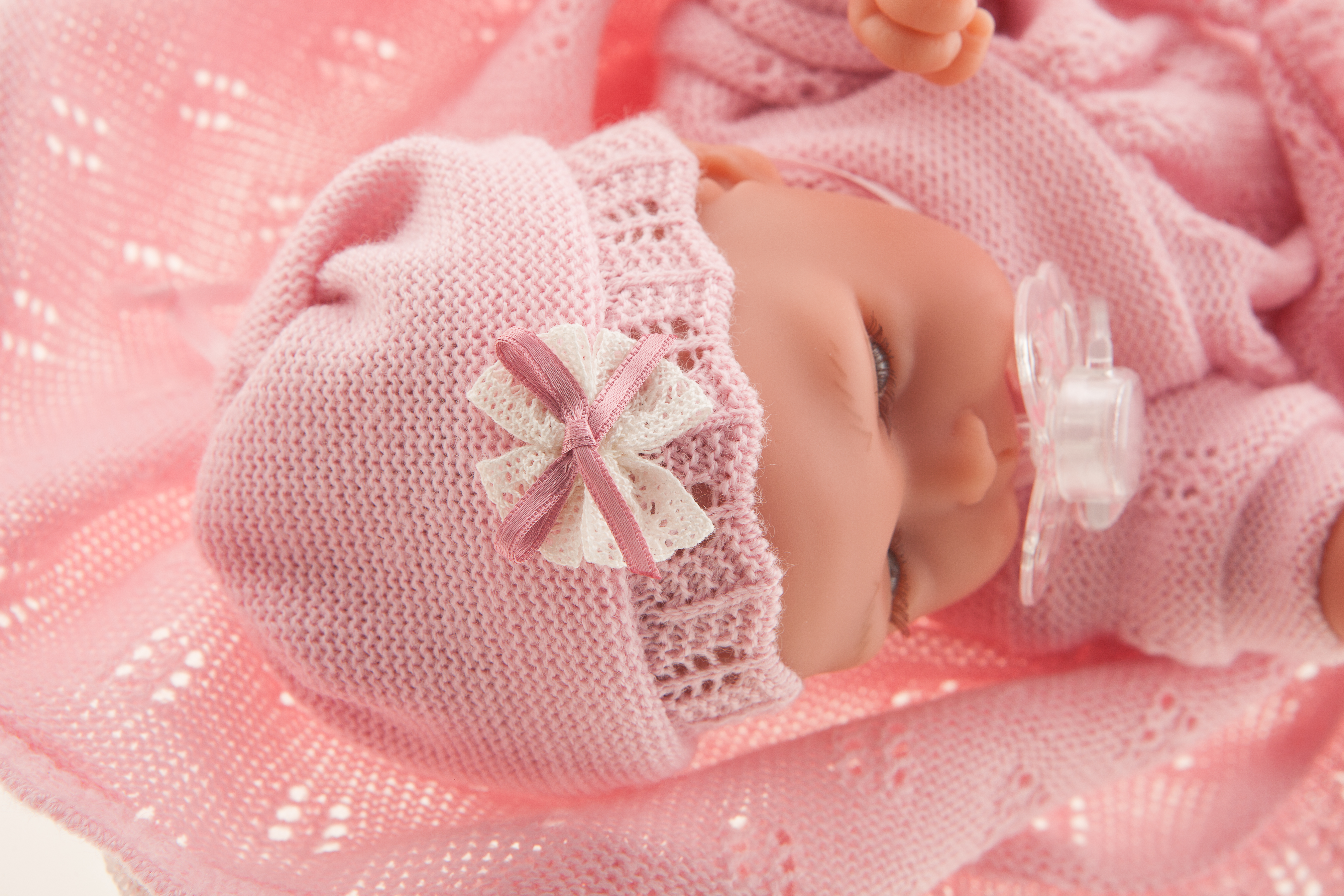 Antonio Juan Babypuppe Peke, schlafendes Gesicht mit Schnuller, rosa Schleifen-Mütze, eingewickelt in die Kuscheldecke