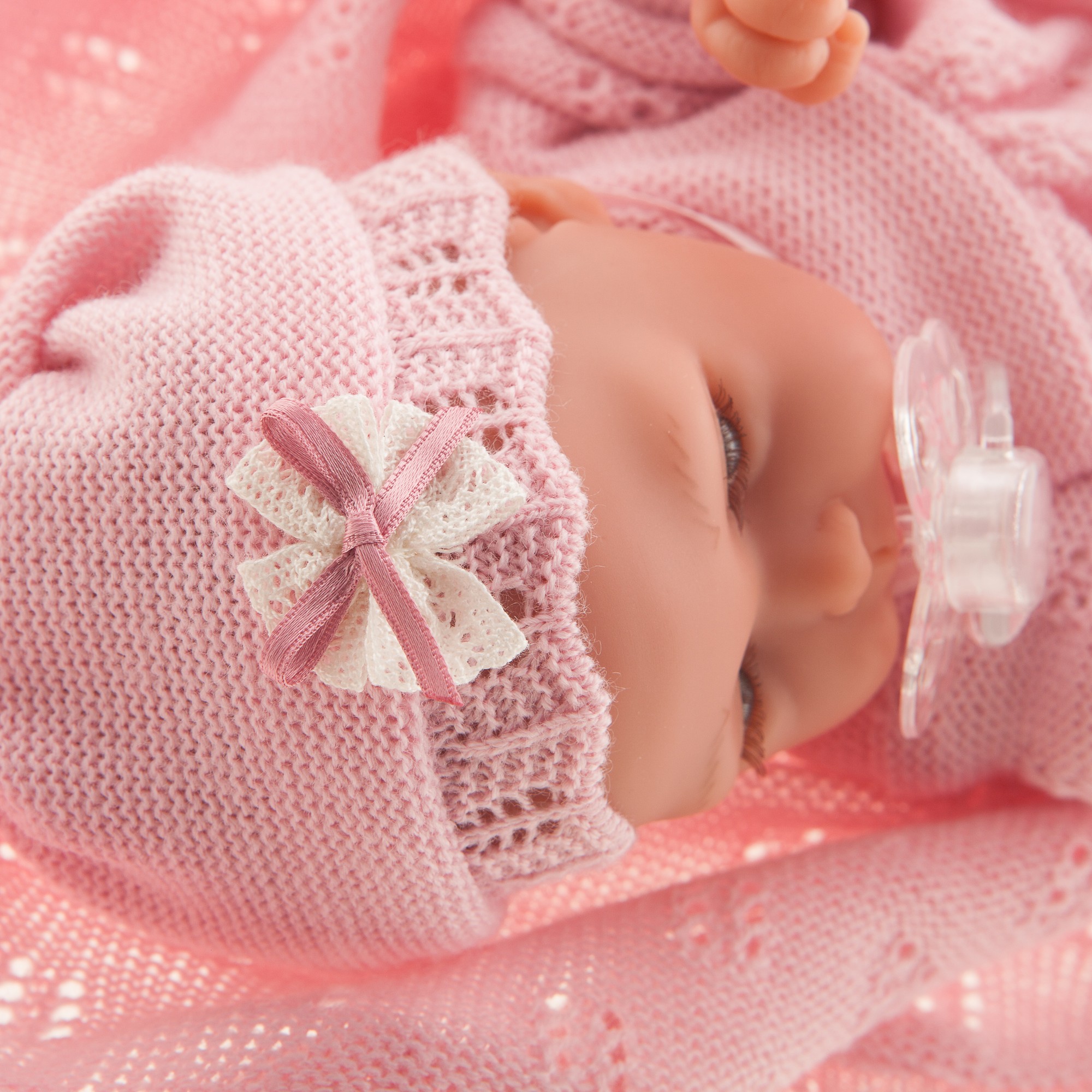 Antonio Juan Babypuppe Peke, schlafendes Gesicht mit Schnuller, rosa Schleifen-Mütze, eingewickelt in die Kuscheldecke