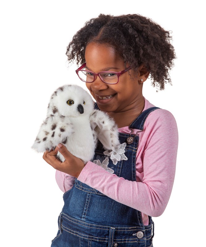 Mädchen hält Folkmanis Handpuppe kleine Schneeeule mit weißem Gefieder und dunklen Flecken in den Händen