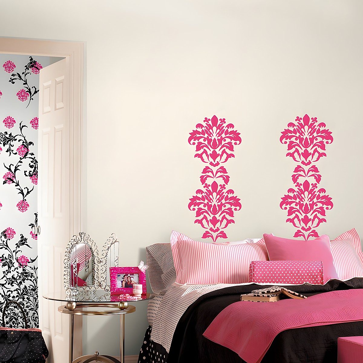 RoomMates wall decal Damask Pink, two pink damask ornaments on a cream-coloured wall above a bed with pink bedding