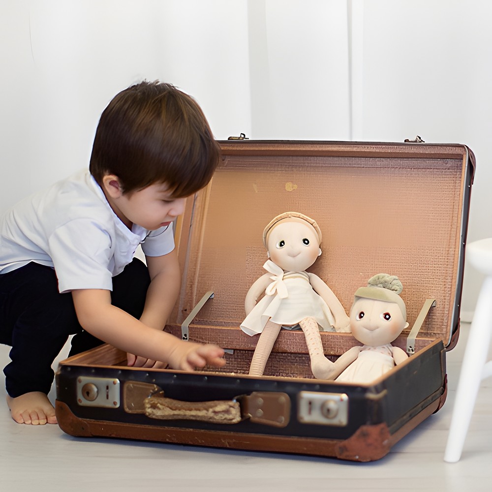 Child putting the Rubens EcoBuds dolls into an old suitcase