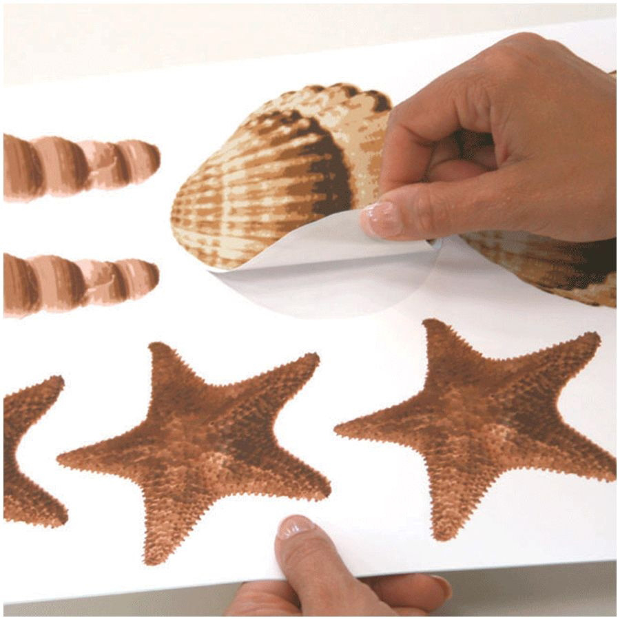 RoomMates Wandsticker Sea Shells Peel & Stick, Hände lösen ein Muschel-Motiv vom Trägerbogen zwischen Seesternen, Anwendungsbeispiel