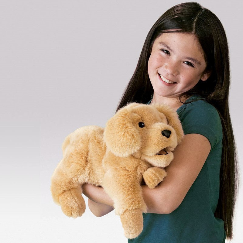 Mädchen hält Folkmanis Handpuppe Golden Retriever Baby mit beweglichem Maul in goldfarbenem Plüsch im Arm