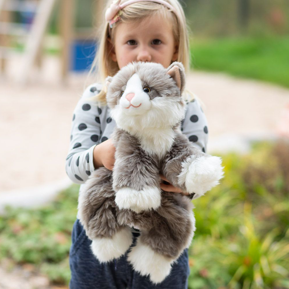 Kind trägt die grau-weiße Joyk Empathiepuppe Billy auf dem Spielplatz