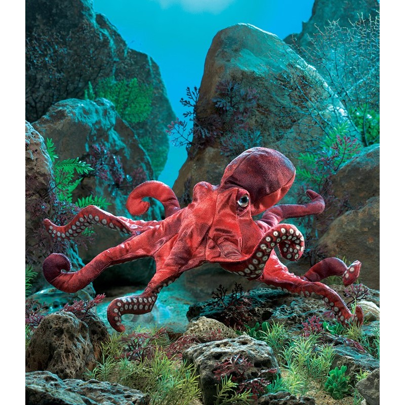 Folkmanis Handpuppe roter Oktopus mit weißen Saugnäpfen an acht Tentakeln, vor inszeniertem Meeresgrund mit Felsen und Algen