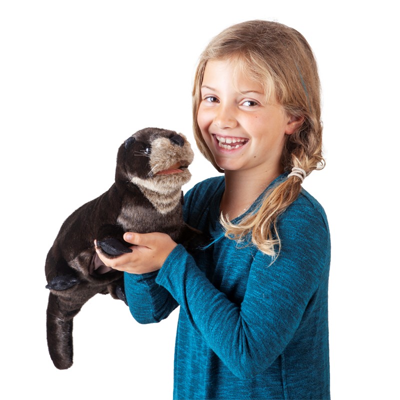 Lächelndes Mädchen hält die Folkmanis Handpuppe Flussotter mit dunkelbraunem Fell und hellem Bauch in beiden Händen.