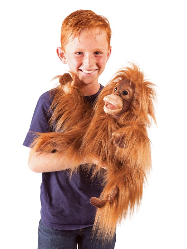 Junge hält Folkmanis Handpuppe Baby Orang-Utan mit rotbraunem Zottelfell und beweglichem Mund vor weißem Hintergrund