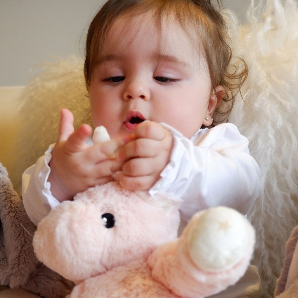 Cloud b sleep aid Ella unicorn, lifestyle close-up of baby touching pink plush toy