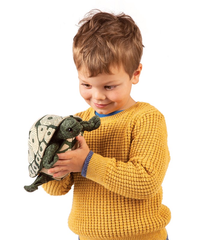 Boy in a yellow jumper holding the Folkmanis tortoise hand puppet with a patterned shell in both hands